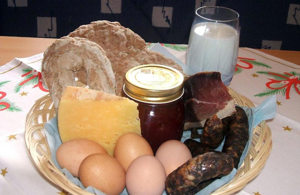 Korb mit Brot, Speck, Wurst, Käse, Marmelade, Eier und Milch vom Hof